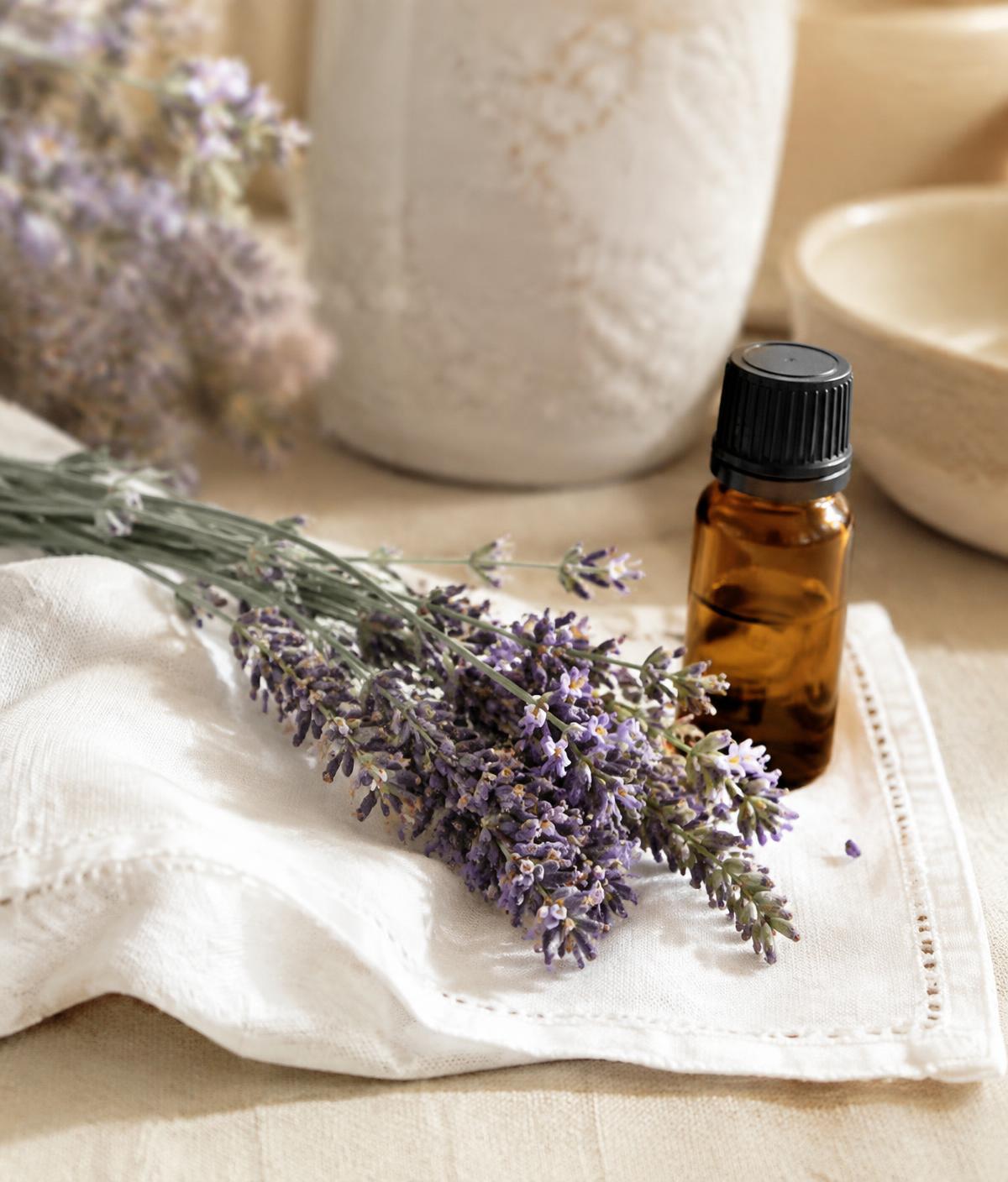 Ramitas de lavanda sobre un pañuelo de lino con un frasco de aceite esencial